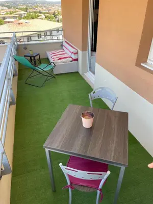 a table and chairs on a balcony with green grass at Charmant appartement hotel calme à Aix en Provence in Aix-en-Provence