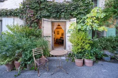 a table and chairs in front of a building with plants at Rock House Pool & Authentic 17th-Century Home in Goult