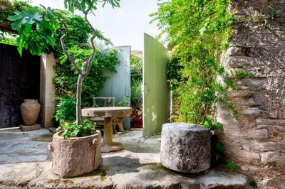 a garden with two large stone pots with a tree in it at Rock House Pool & Authentic 17th-Century Home in Goult