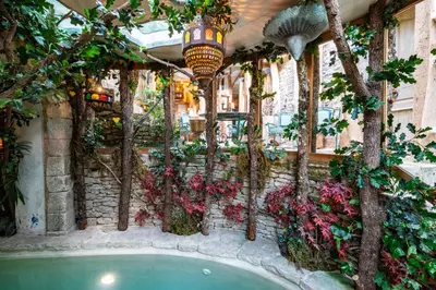 a pool in a building with flowers and trees at Rock House Pool & Authentic 17th-Century Home in Goult