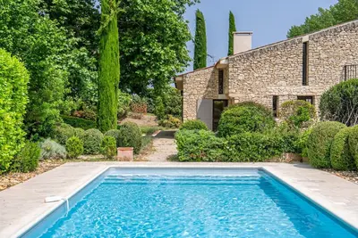 a swimming pool in front of a stone house at Magnifique villa au coeur de la campagne de Gordes in Gordes