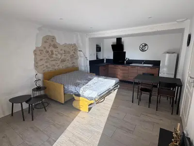 a bedroom with a bed and a kitchen with a table at Studio Rénové de Charme en Provence in Caumont-sur-Durance