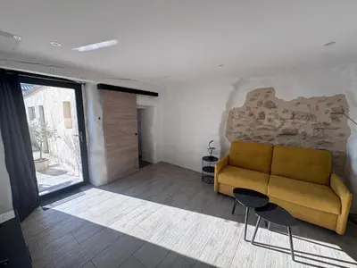 a living room with a yellow couch and a large window at Studio Rénové de Charme en Provence in Caumont-sur-Durance