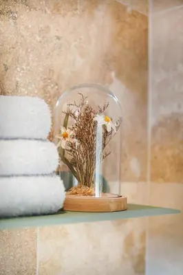 a glass jar with flowers on a shelf next to towels at L Appartement 1 Chambre - Gîte la Bergerie du Ventoux in Mormoiron