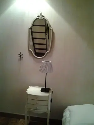 a lamp on a table with a mirror on a wall at Mas De Hameau in Oppède