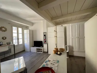 a living room with white cabinets and a television at Chez Anne - Appartement cosy avec mezzanine au cœur du centre historique d'Aix-en-Provence in Aix-en-Provence