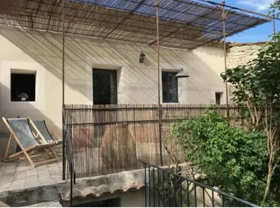 a house with a chair on a patio at Le cabanon in Saint-Martin-de-Castillon