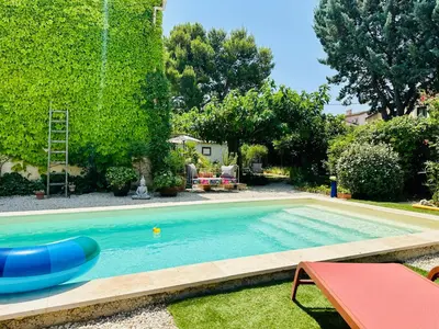 a swimming pool with a blue raft in a yard at Havre de paix proche centre ville, jardin, piscine in LʼIsle-sur-la-Sorgue