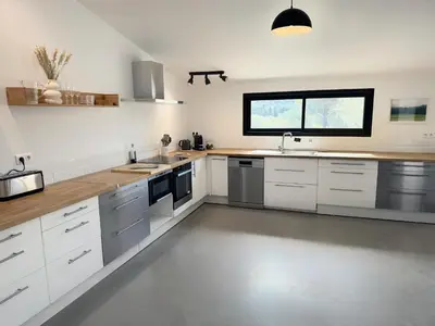 a large kitchen with white cabinets and a window at La Villa des Glauges in Eyguières