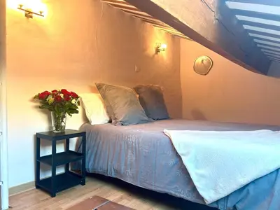 a bedroom with a bed with a vase of flowers on a table at Charmante maison de village avec clim et parking à proximité d'Aix-en-Provence in Éguilles
