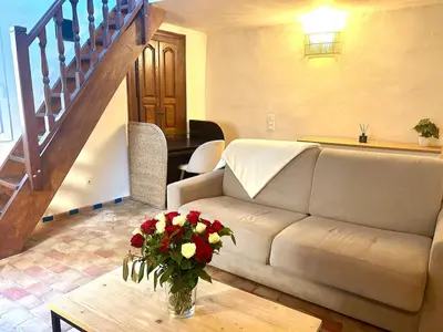 a living room with a couch and a table with flowers at Charmante maison de village avec clim et parking à proximité d'Aix-en-Provence in Éguilles