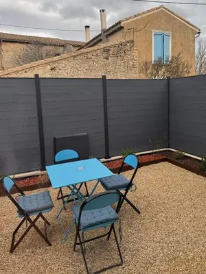 two chairs and a table on a patio with a fence at Esprit Lubéron, La Lavande, logement entier in Le Thor