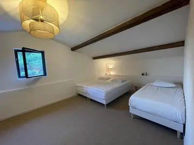 a bedroom with two beds and a window and a chandelier at Luberon house with view in Cucuron