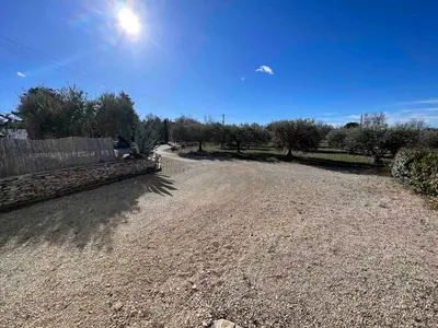 a gravel road with a fence and trees in a field at Le gîte des granges in Bédoin