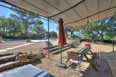 an umbrella and a chair and a bench and a table at Bergerie provencale, 4 personnes, piscine in Gordes