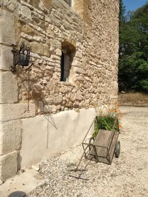a cart of grass sitting next to a stone building at Les feuillets de la Buire in Monteux