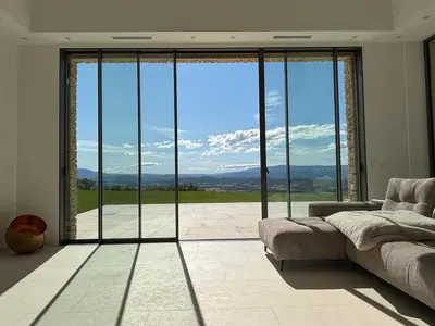 a living room with a couch and a large glass window at 180 Grand Luberon Gordes vue panoramique in Gordes