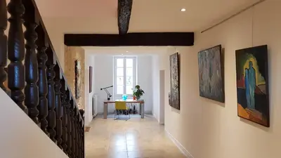 a hallway with paintings on the walls and a table at Domaine De Pradaous in Reillanne