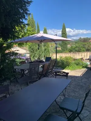 a patio with tables and chairs and an umbrella at La Commanderie du Ventoux in Mormoiron