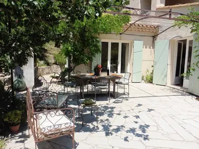 a patio with a table and chairs in a yard at Holiday Home Charmantes Landhaus mit Garten by Interhome in Pierrevert