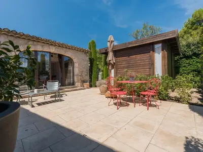 a patio with red chairs and a table and a bench at Holiday Home Das Atelier im Mas Naste by Interhome in Eygalières