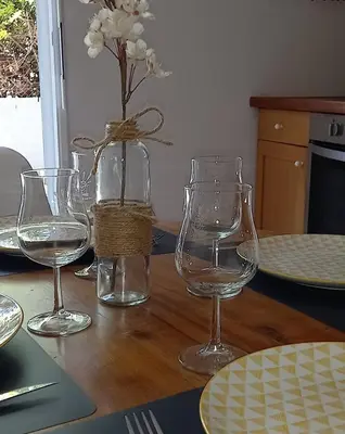a table with three wine glasses and a vase with flowers at Hébergement tout confort au pied du Luberon in Cabrières-dʼAigues