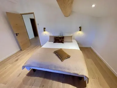 a bedroom with a large bed with a wooden floor at Lourmarin, Maison De Charme Au Coeur Du Luberon in Cadenet