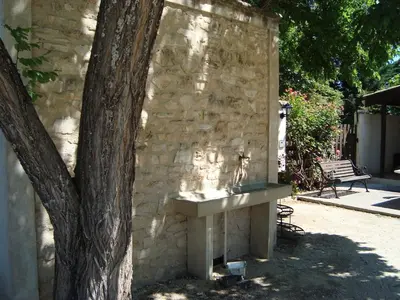 a stone wall with a sink next to a tree at Danie, maison des oliviers et vue Luberon in Maubec