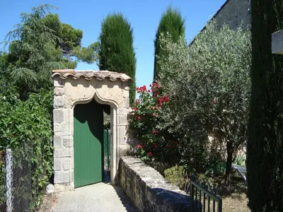 a green door in a stone archway in a garden at Danie, maison des oliviers et vue Luberon in Maubec