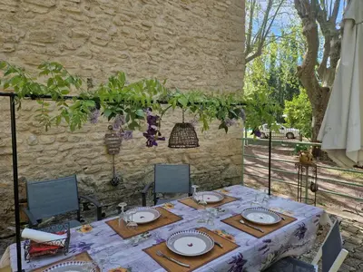 a table with plates on it in front of a stone wall at Gîte Moulin de l'Anet in Goult