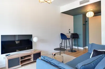 a living room with a blue couch and a tv at Downtown suite, parking, loggia, elevator, quiet in Aix-en-Provence