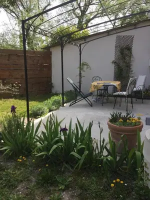 a patio with a table and chairs under a pergola at Le Petit Pont - Au bord de la rivière in LʼIsle-sur-la-Sorgue