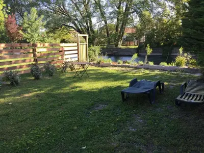 a yard with two benches and a table and a fence at Le Petit Pont - Au bord de la rivière in LʼIsle-sur-la-Sorgue