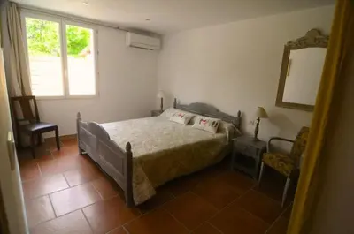 a bedroom with a bed and a chair and a mirror at Le Petit Pont - Au bord de la rivière in LʼIsle-sur-la-Sorgue
