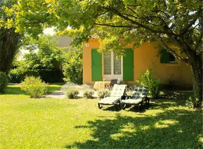 a house with two chairs and a tree in the yard at Le Castor et La Loutre - Gites en bord de Sorgue in LʼIsle-sur-la-Sorgue