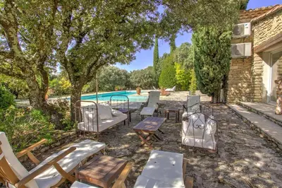 a patio with chairs and tables and a pool at La Garrigue de Gordes in Gordes