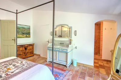 a bedroom with a bed and a bathroom with a sink at La Garrigue de Gordes in Gordes