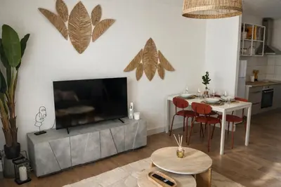 a living room with a television and a table with chairs at Appartement 4 personnes 5 minutes a pieds du centre ville parking gratuit jardin 85m2 in LʼIsle-sur-la-Sorgue
