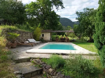 a swimming pool in a garden with a table and chairs at le Mas caché in Ménerbes