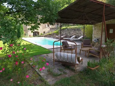a patio with chairs and an umbrella next to a swimming pool at le Mas caché in Ménerbes