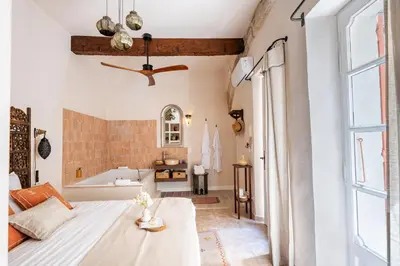 a bedroom with a bed and a tub in a room at La Cour Secrète - 2 Suites avec Balnéo privée in Carpentras