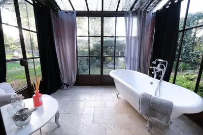 a bath tub in a room with windows at luxury farm jacuzzi heated pool in Isle sur la sorgue in Lagnes