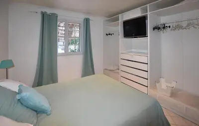 a white bedroom with a bed and a television at Maison Avec Piscine Privée in Entraigues-sur-la-Sorgue