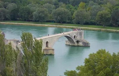 a group of people crossing a bridge over a river at Maison Avec Piscine Privée in Entraigues-sur-la-Sorgue