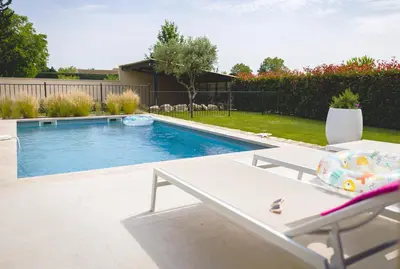 a swimming pool with a table and a chair next to it at Le mas des cerisiers - piscine chauffée in Caumont-sur-Durance