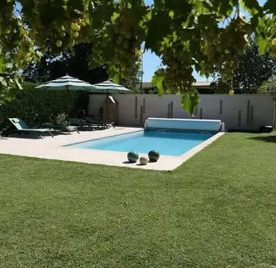 a swimming pool in a yard with chairs and umbrellas at Les terrasses di Matt et eaux in LʼIsle-sur-la-Sorgue