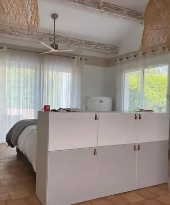 a bedroom with white cabinets and a bed with windows at Les terrasses di Matt et eaux in LʼIsle-sur-la-Sorgue