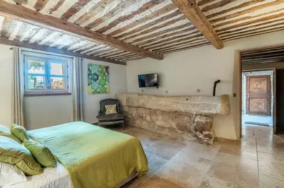 a bedroom with a bed and a stone wall at Wine Estate With Sunset Courtyard Near Bédoin in Mazan