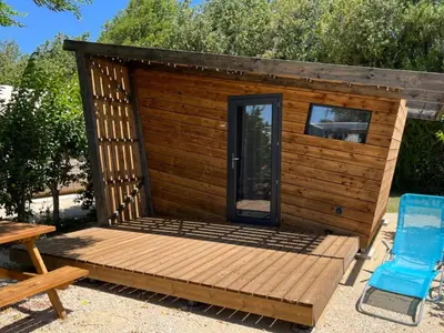a wooden cabin with a table and a blue chair at Mobil Home PMR avec Terrasse à Cavaillon - API-1-52-1378 in Cavaillon