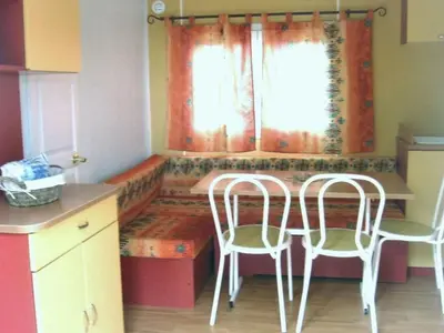 a kitchen with two chairs and a table and a window at Mobil-home 32m² avec terrasse, 3 chambres à Cavaillon, 8 pers. - API-1-52-1384 in Cavaillon